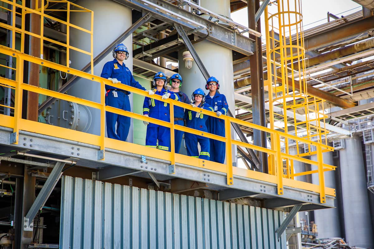 Operations crew in coveralls and hard hats on a platform at a processing plant